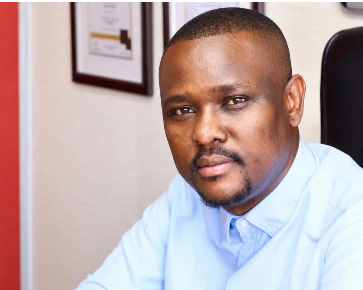 Mothusi Molokomme in a light-blue shirt in a professional office portrait.