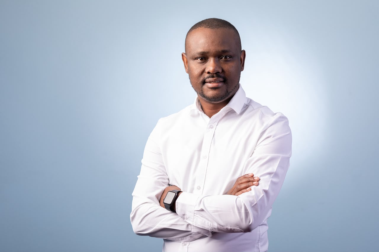 Mothusi Molokomme in a white shirt against a light-blue studio background.